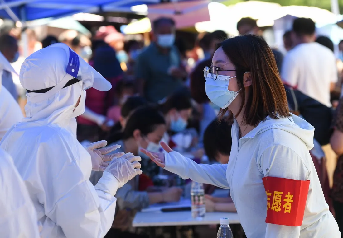 7月21日，在南京市江宁区万科金域蓝湾小区核酸检测点，医生和社区志愿者交流。新华社记者 季春鹏 摄
